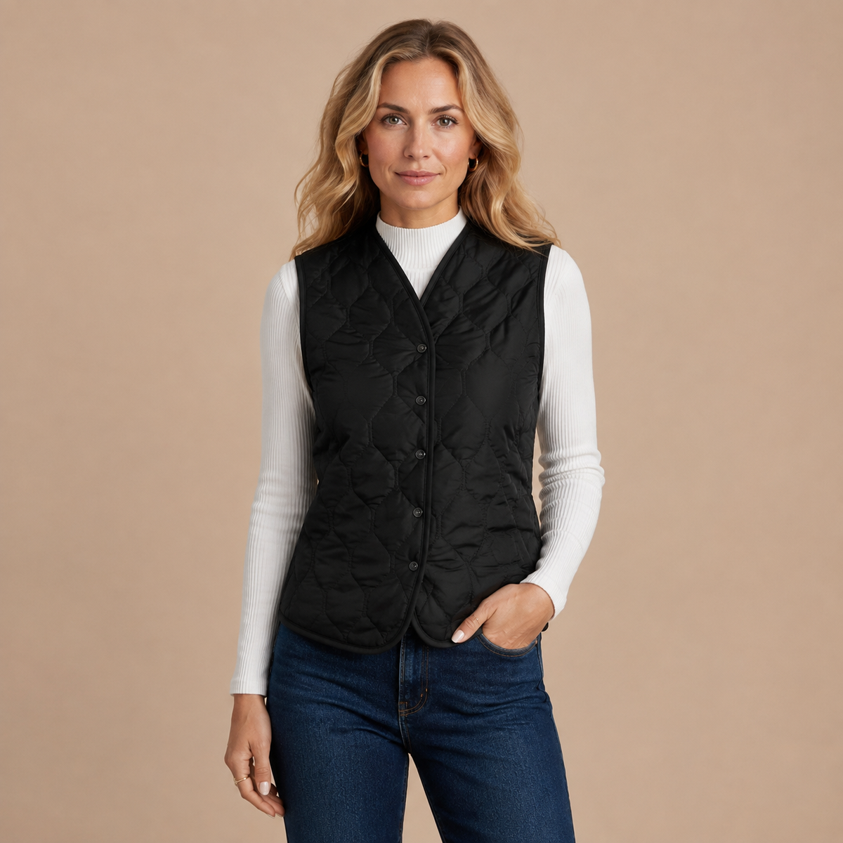 Zwart gewatteerd damesgilet met knoopsluiting, gedragen over een witte top.