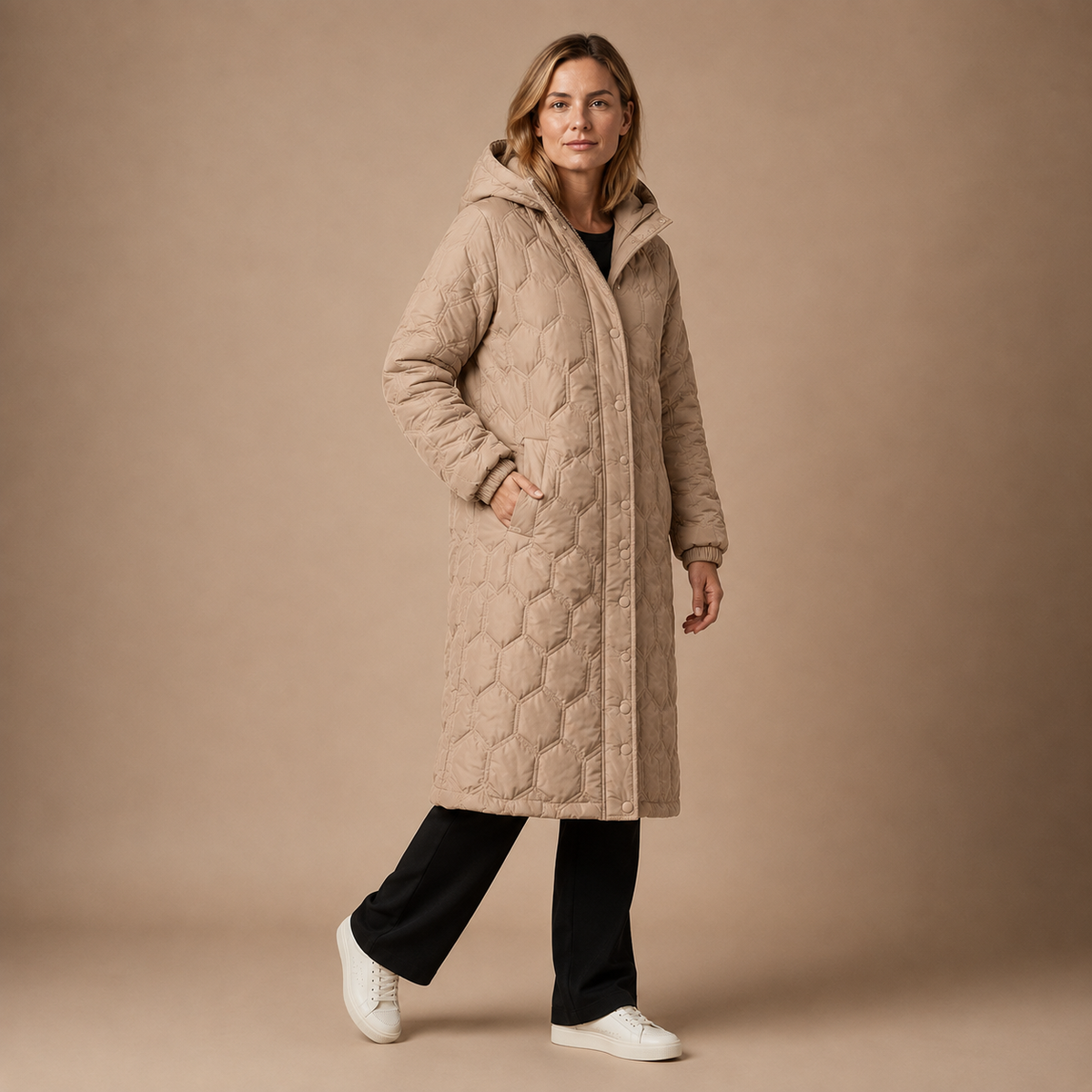 Beige lange gewatteerde dameswinterjas met capuchon en doorgestikt patroon.