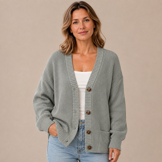 Grijsgroen damesvest met V-hals en knopen, gedragen met een witte top en jeans
