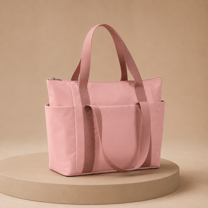 Roze shopper met lange hengsels en meerdere buitenvakken, vrijstaand op een ronde sokkel.