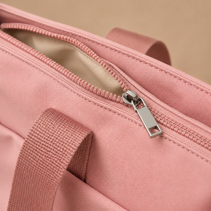 Detail van de ritssluiting, hengsels en naden van een roze shopper.