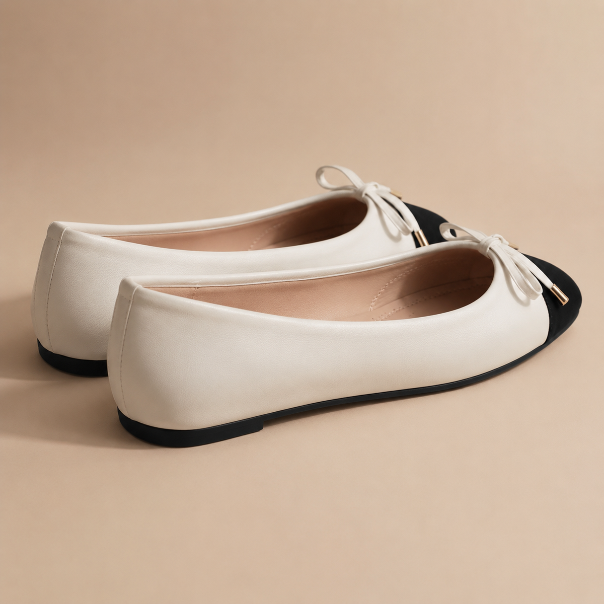 Achter- en zijaanzicht van crèmekleurige ballerina's met zwarte neus en platte zool.