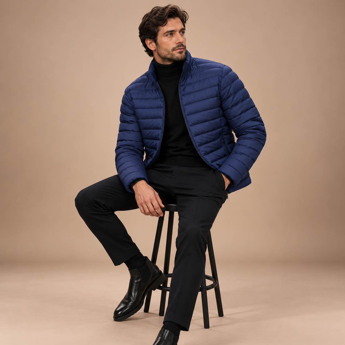 Marineblauwe gewatteerde winterjas heren zittende studio pose