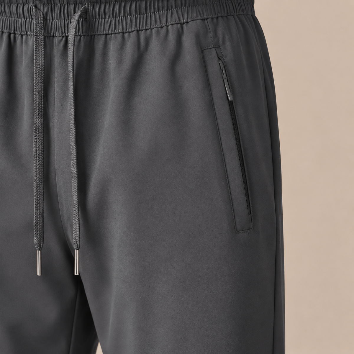 Joggingbroek Heren Lichtgewicht - Casual Trainingsbroek met Ritszakken en Trekkoord in grijs – detailopname op beige studioachtergrond