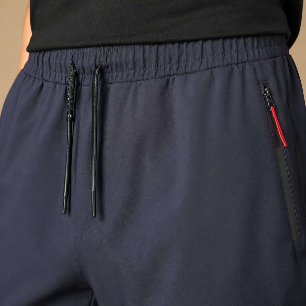 Joggingbroek Heren Sportief - Trainingsbroek met Ritszakken en Trekkoord in marineblauw – detailopname op beige studioachtergrond