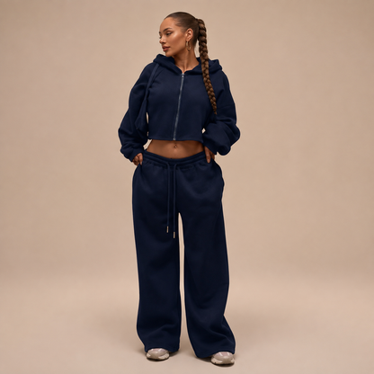 Donkerblauw damesjoggingpak met korte ritshoodie en wijde broek, vooraanzicht.