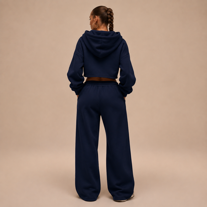 Achteraanzicht van een donkerblauw damesjoggingpak met cropped hoodie en wijde broek.