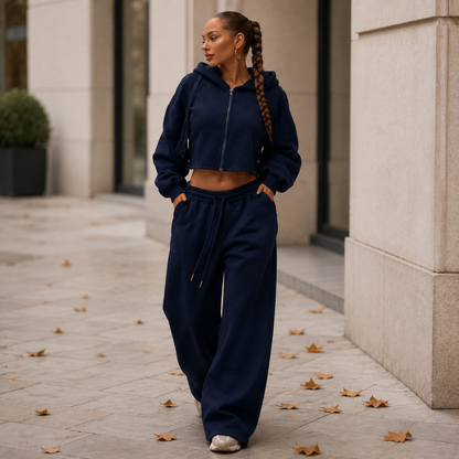 Donkerblauw damesjoggingpak met korte hoodie en wijde broek, gedragen op straat.