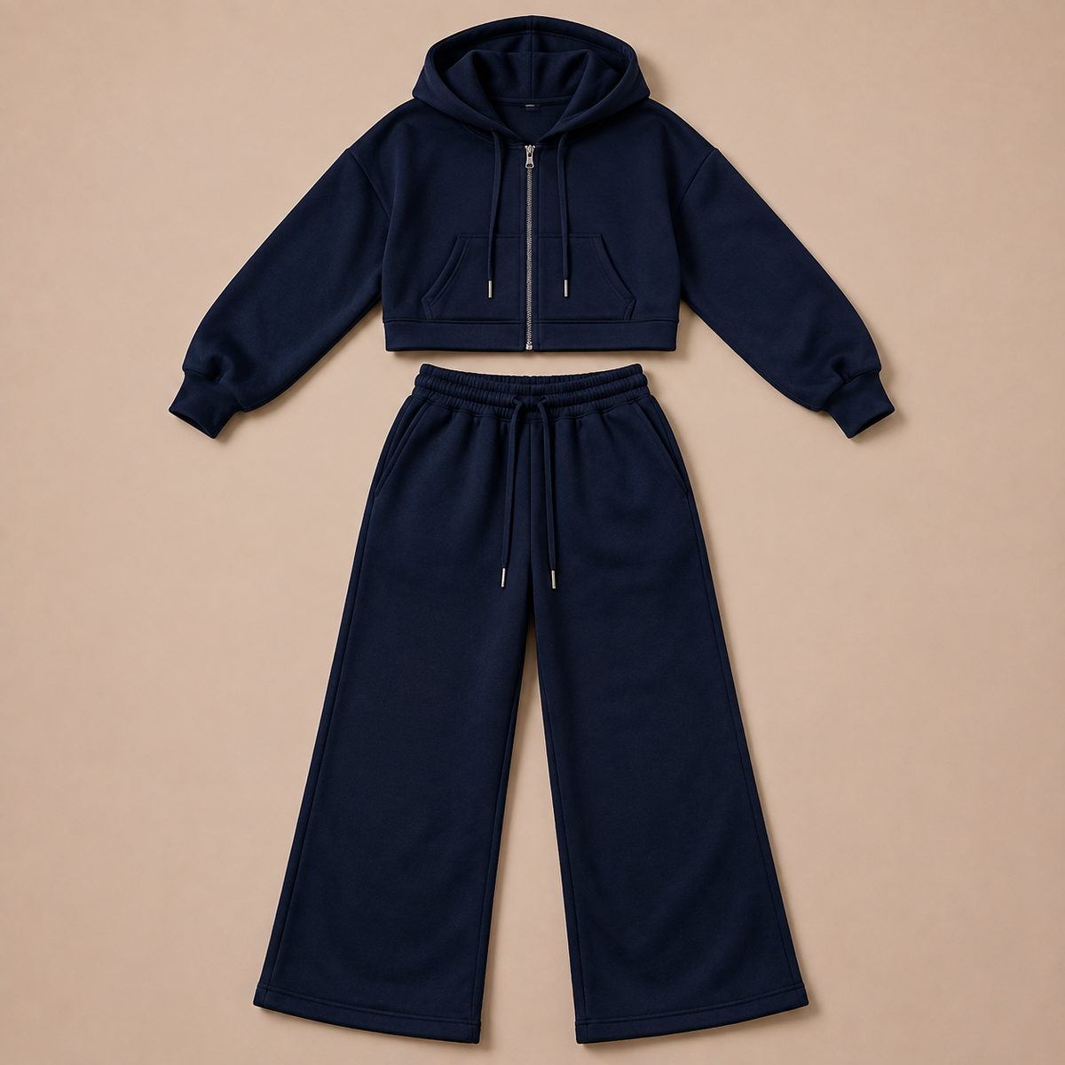 Donkerblauw damesjoggingpak met cropped ritshoodie en wijde broek, plat neergelegd.