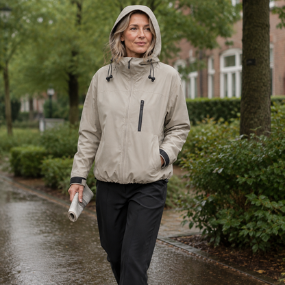 Beige korte damesjas met capuchon, gedragen tijdens een wandeling op een nat pad.