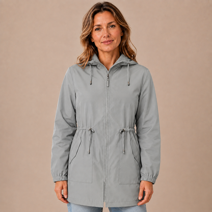 Regenjas dames lang – waterafstotende parka met capuchon en taillekoord in grijs – vooraanzicht op beige studioachtergrond