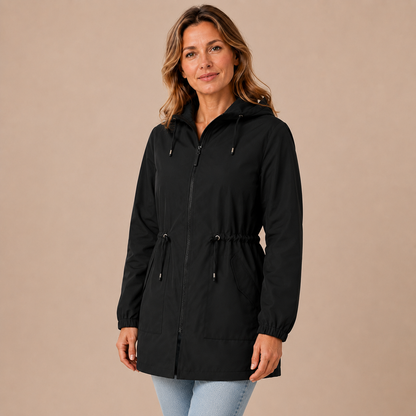 Regenjas dames lang – waterafstotende parka met capuchon en taillekoord in zwart – driekwartaanzicht op beige studioachtergrond