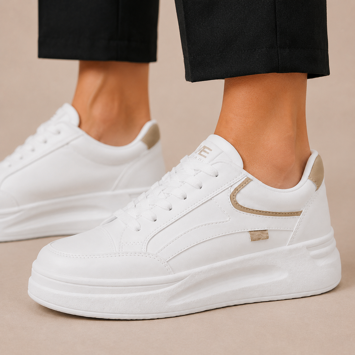 Detail van de veters, stiksels en beige accenten op een witte platformsneaker.