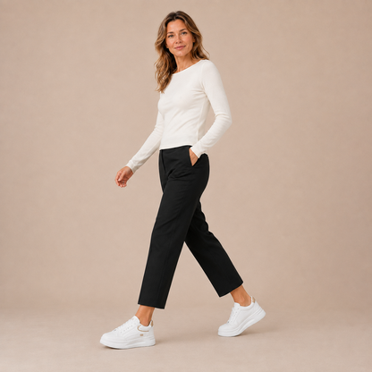 Witte platformsneakers aan een lopend model met een zwarte enkelbroek.