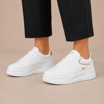 Witte lage damessneakers met veters en een dikke platformzool, aan de voeten.