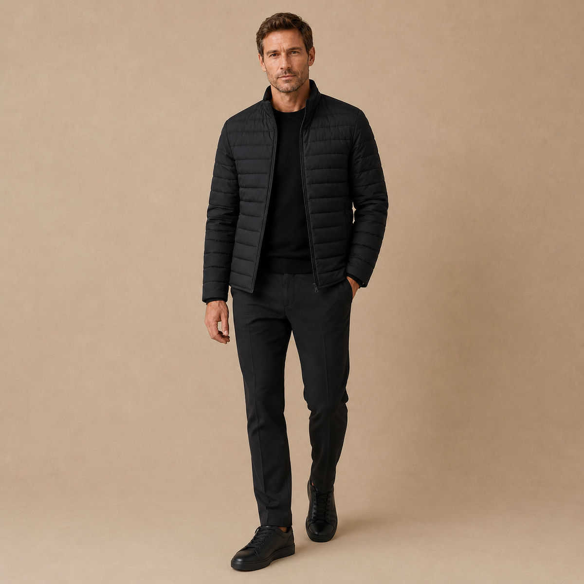 Model draagt een zwarte licht gewatteerde herenjas met zwarte broek en schoenen